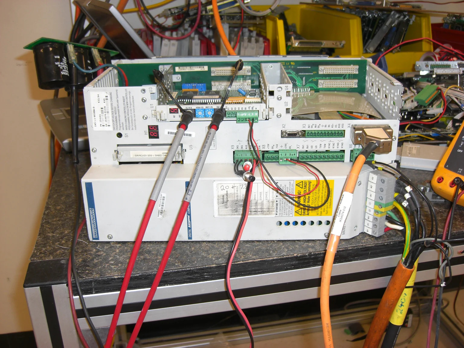 Litco repair-bench reference of a DKS01.1-W100A-DL01-00-FW drive with its cover open and diagnostic leads attached